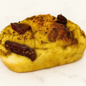 Freshly baked Enchanted Garden Focaccia topped with pesto and sun-dried tomatoes, golden and rustic with a magical twist.