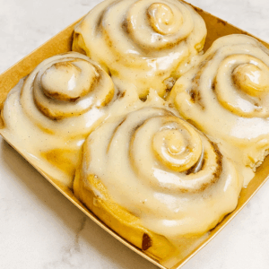 Brown butter vanilla bean cinnamon rolls drizzled with creamy vanilla glaze, styled in a cozy winter setting.