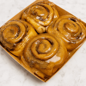 Freshly baked cookie butter cinnamon rolls drizzled with creamy cookie butter glaze, styled on a rustic winter background.